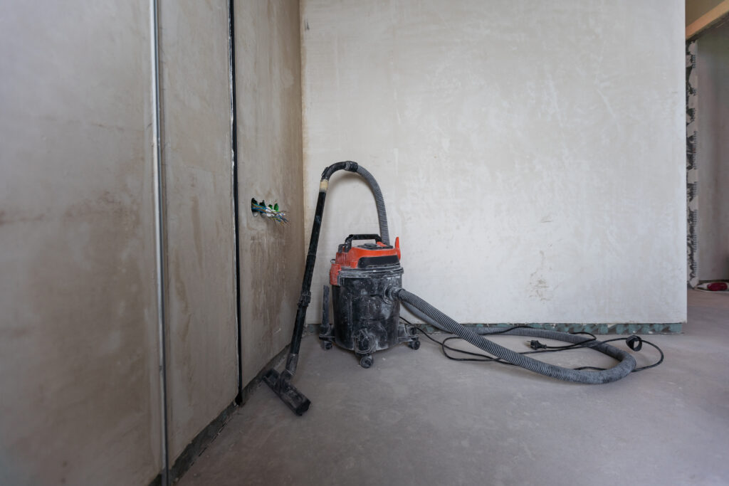 Industrial Vacuum Cleaner On The Dusty Floor Of Construction Site.