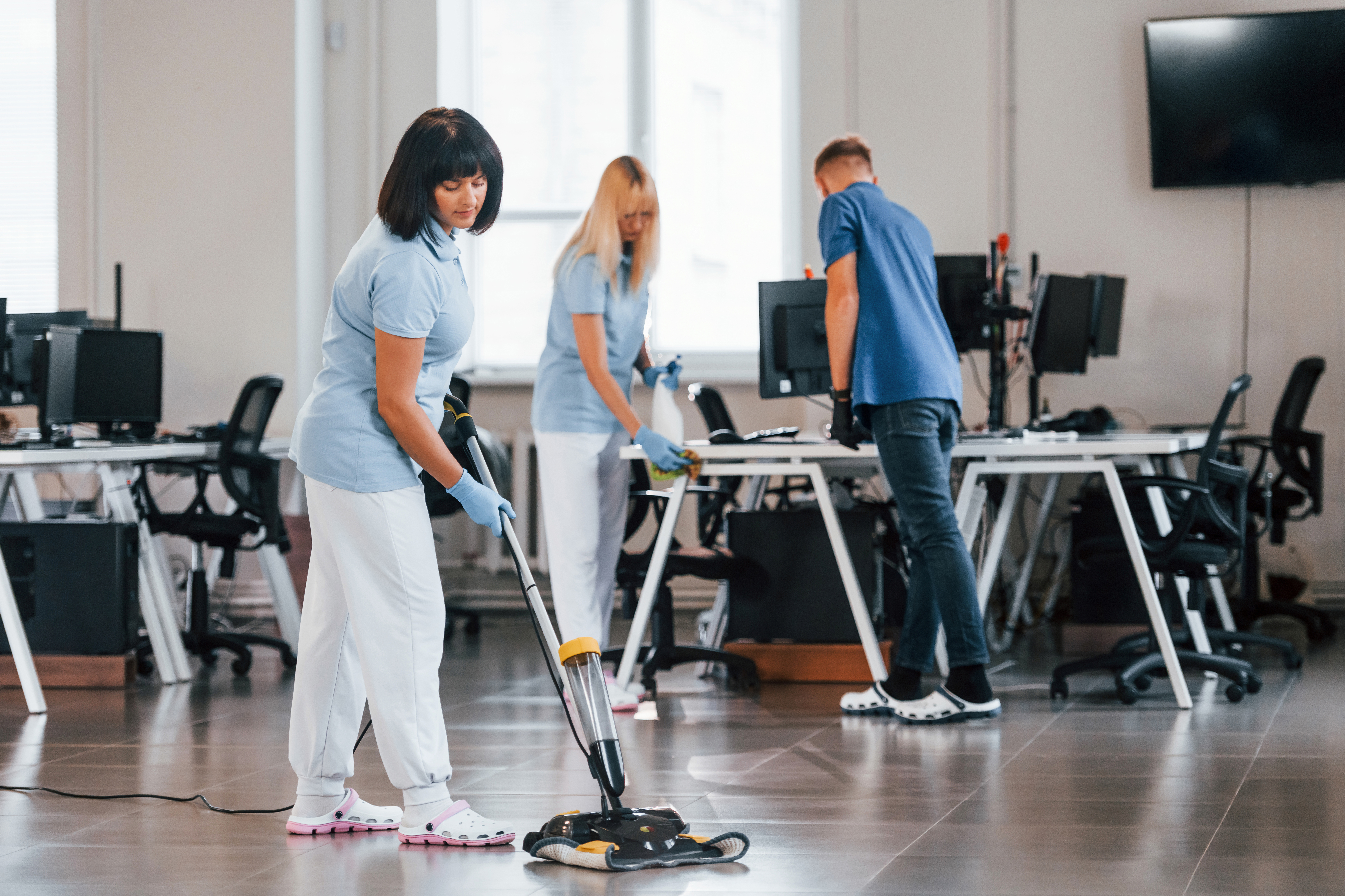 Woman Uses Vacuum Cleaner. Group OUne femme utilise un aspirateur. Groupe de travailleurs nettoyant un bureau moderne ensemble à l'heure du jourf Workers Clean Modern Office Together At Daytime